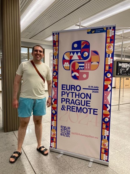 Medium-size man with light green shirt, cyan short, and sandals beside Euro Python poster